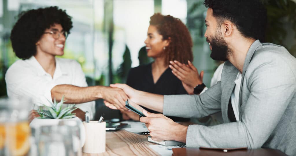 Handshake, team and happy business people with agreement, sponsorship and b2b partnership. Smile, meeting and shaking hands with group for cooperation, deal offer and clapping with tablet in office.