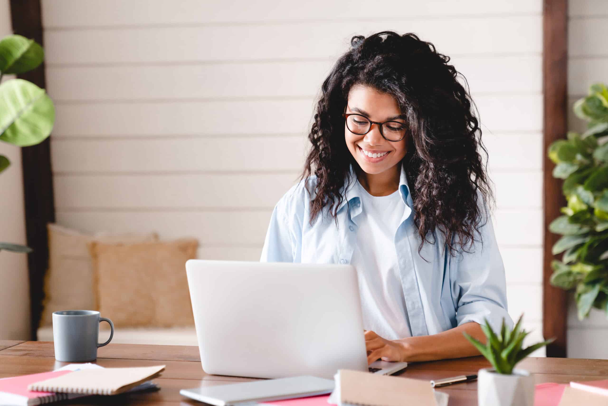 Happy successful young african-american businesswoman working on laptop. African girl school student e learning distance training course study work at home office. Ethnic young woman watching online education webinar using laptop.