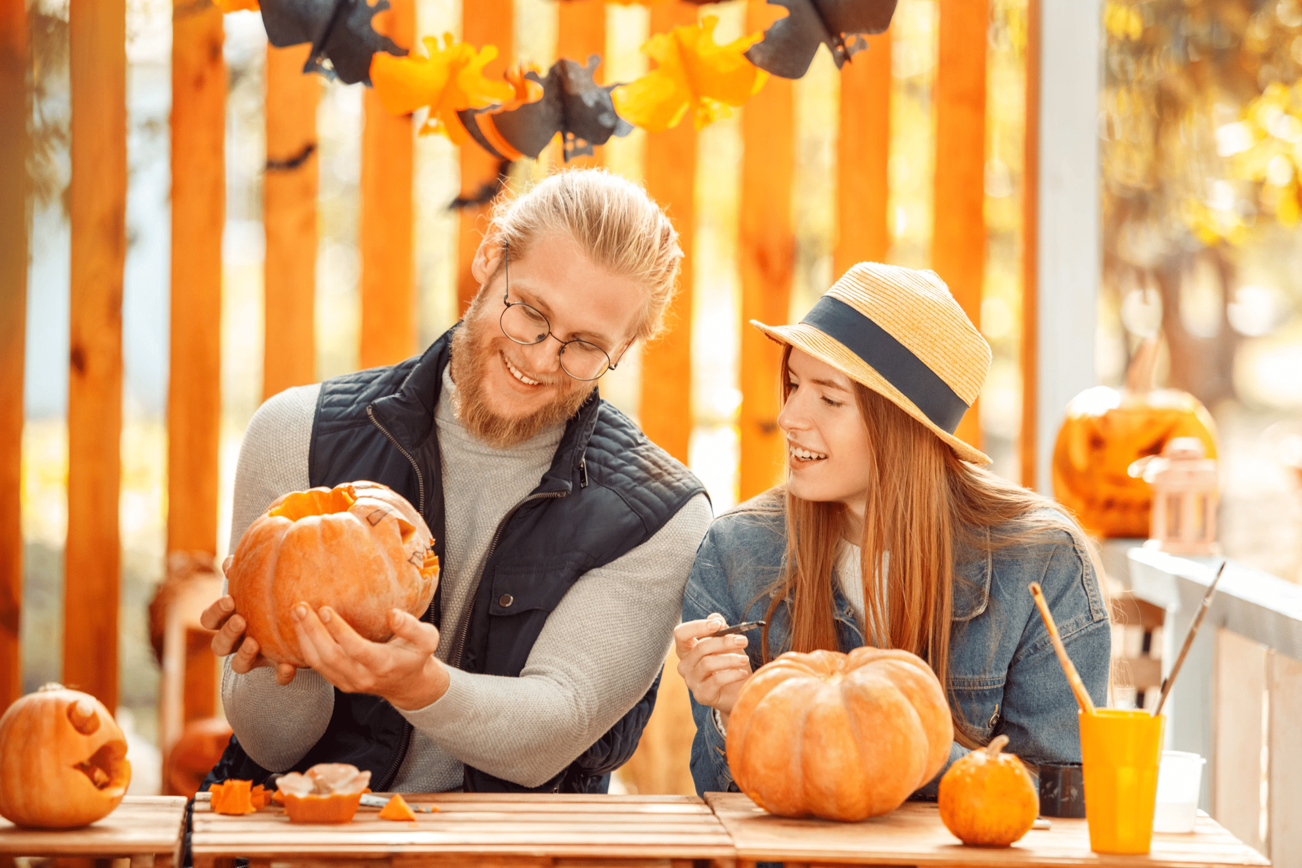 A couple of college students carving pumpkins together