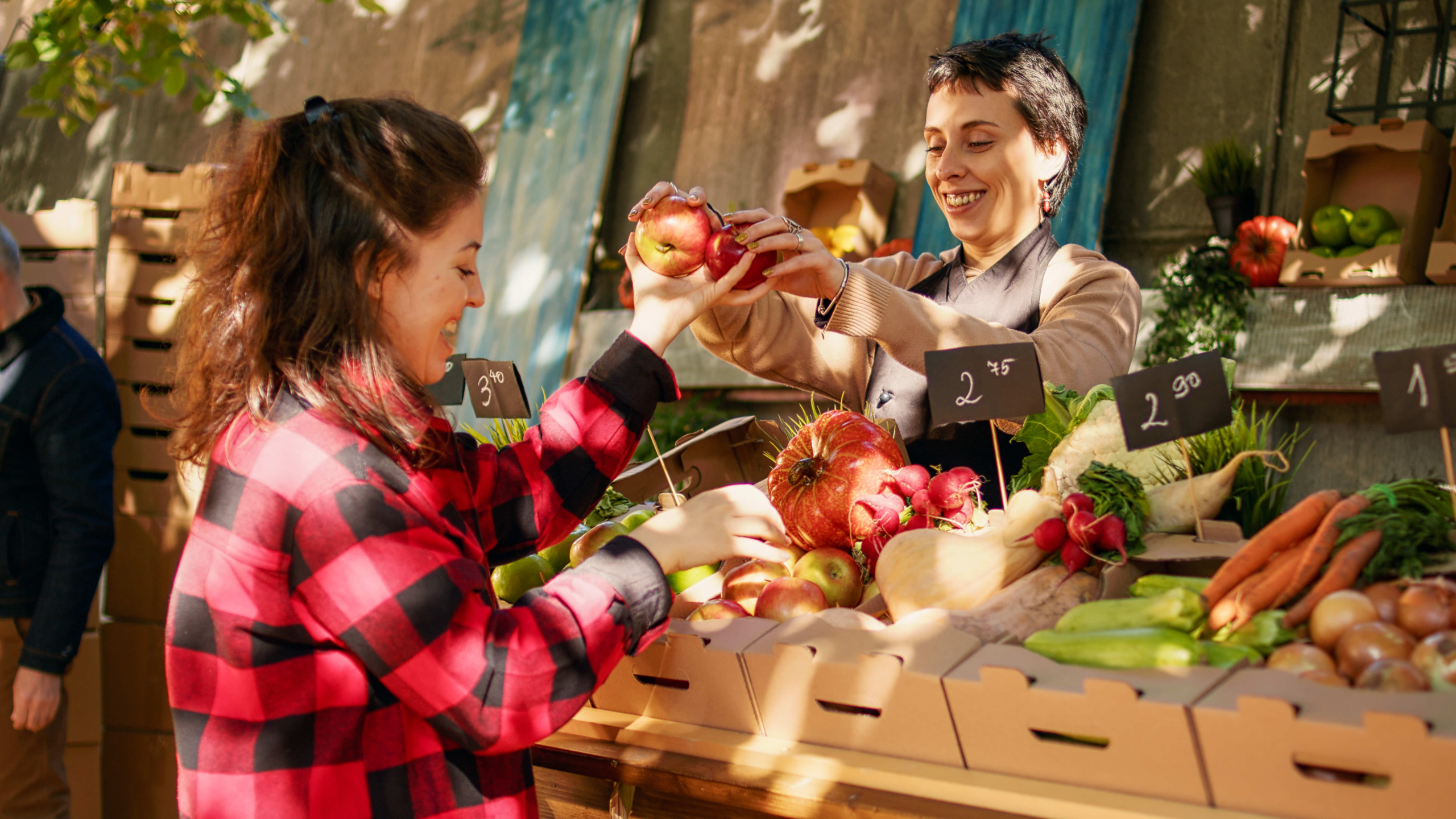 A college student buying apples from a vendor at a local farmers market