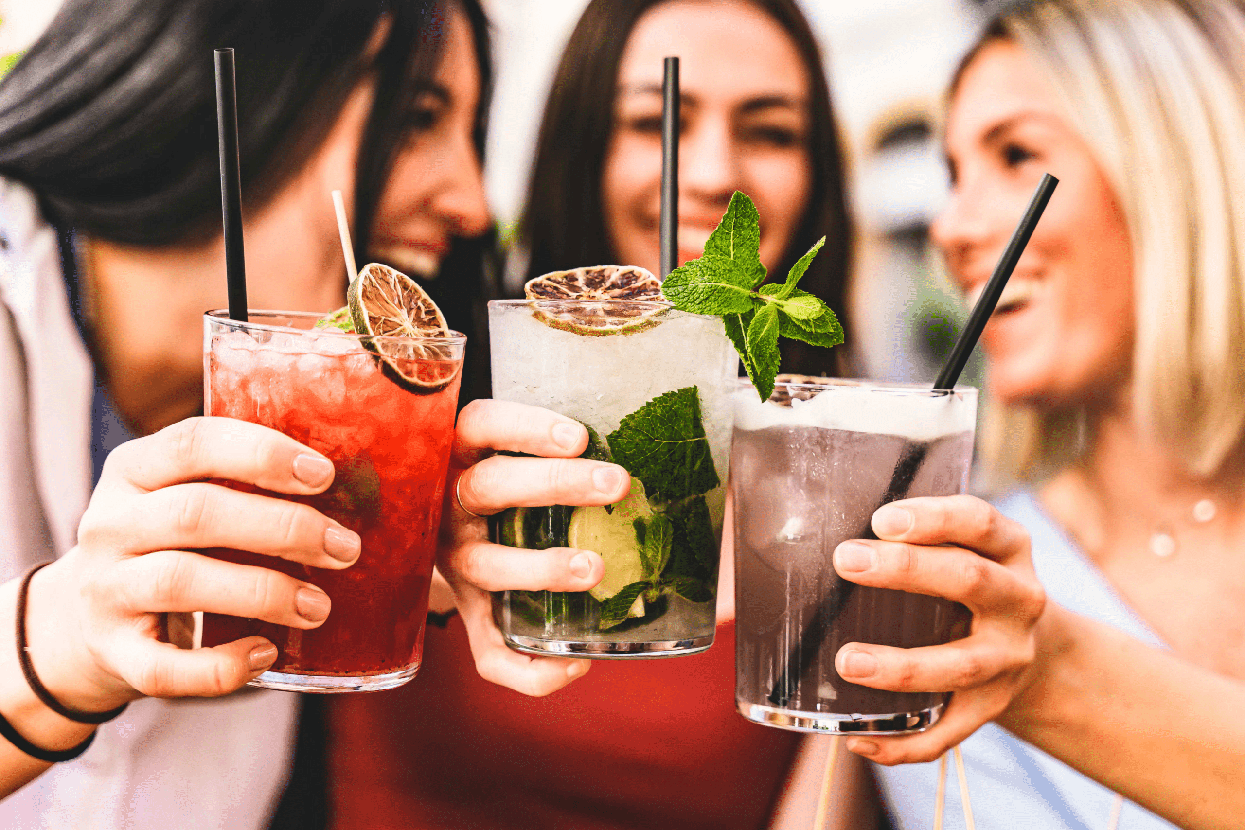 three girls clinking their cocktail drinks