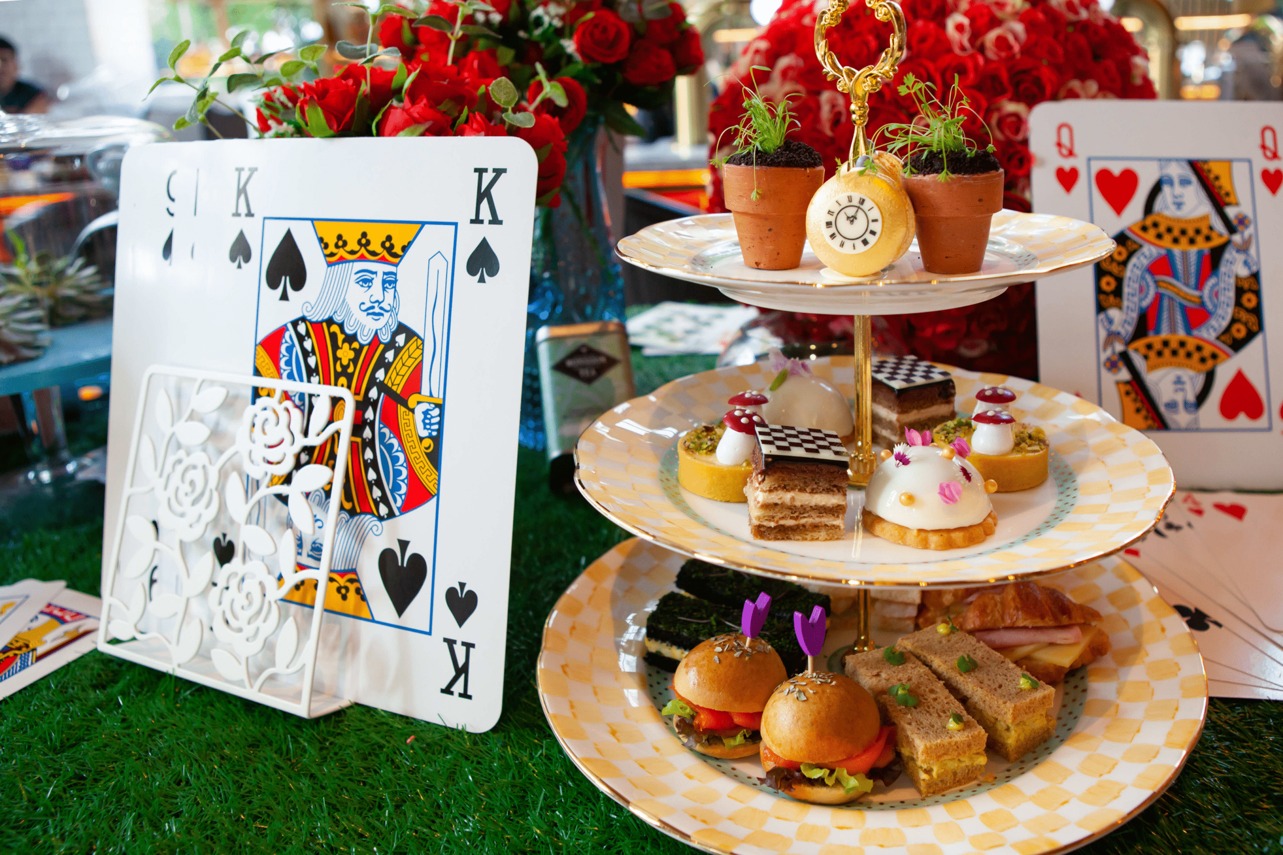 a platter of cupcakes and decorative playing cards at a Alice in Wonderland summer party