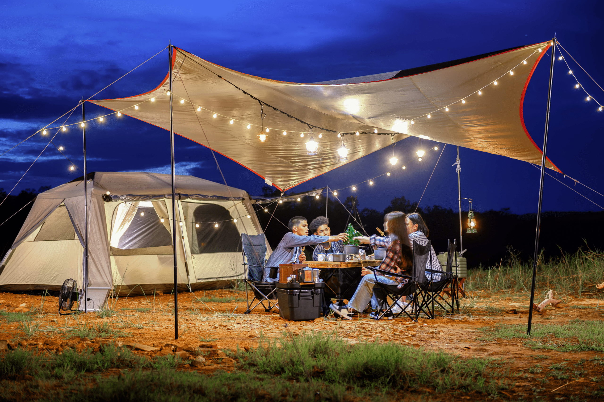 high-end tent with fairy lights that a group of people are eating together under