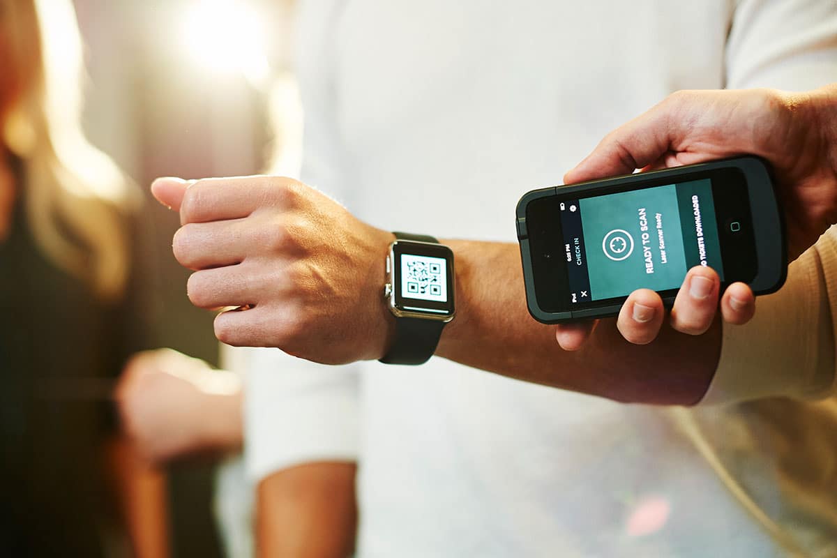 A person scanning a QR code on a smartwatch on their smartphone