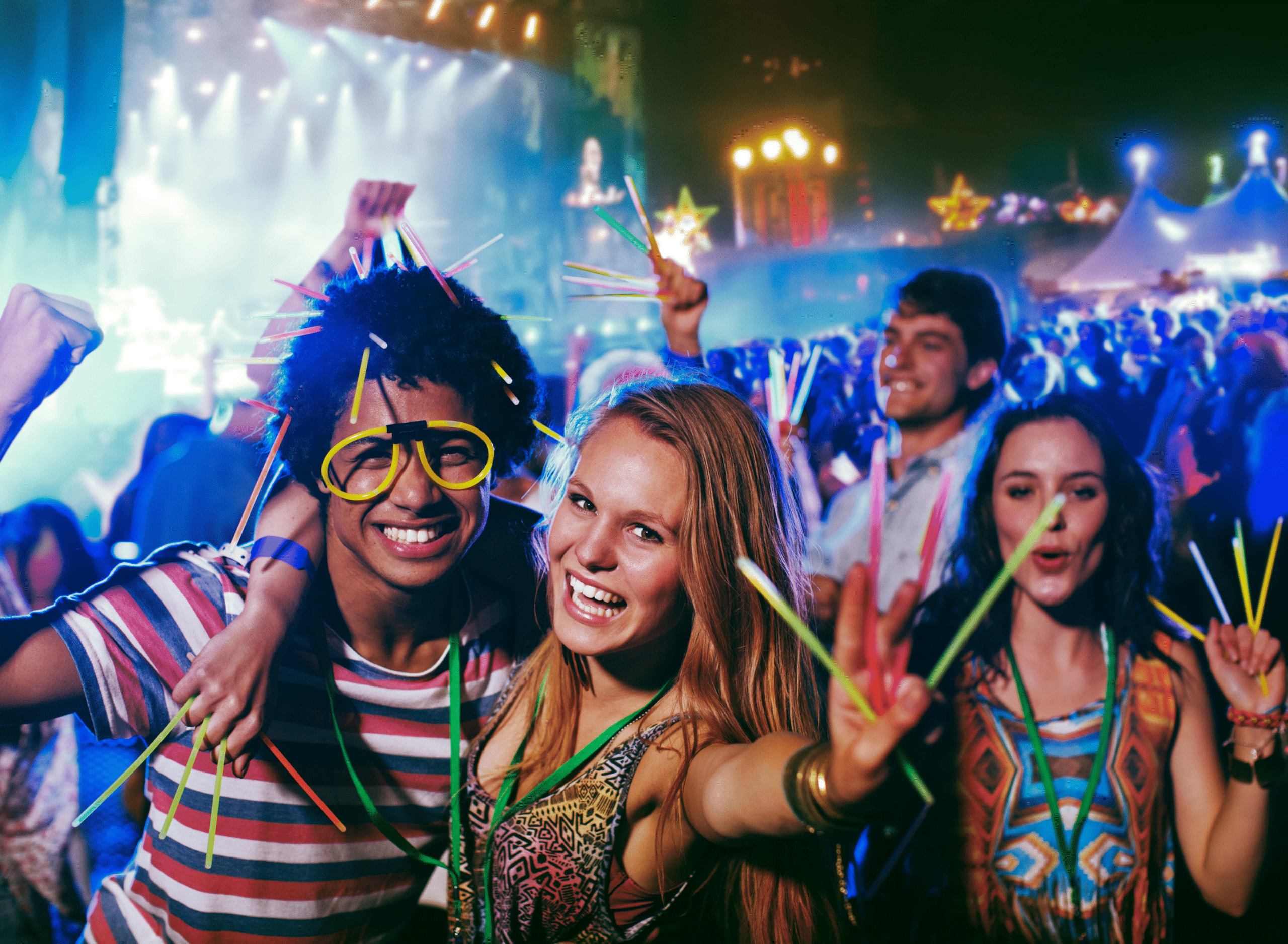 young people at a summer party, holding and wearing glow sticks