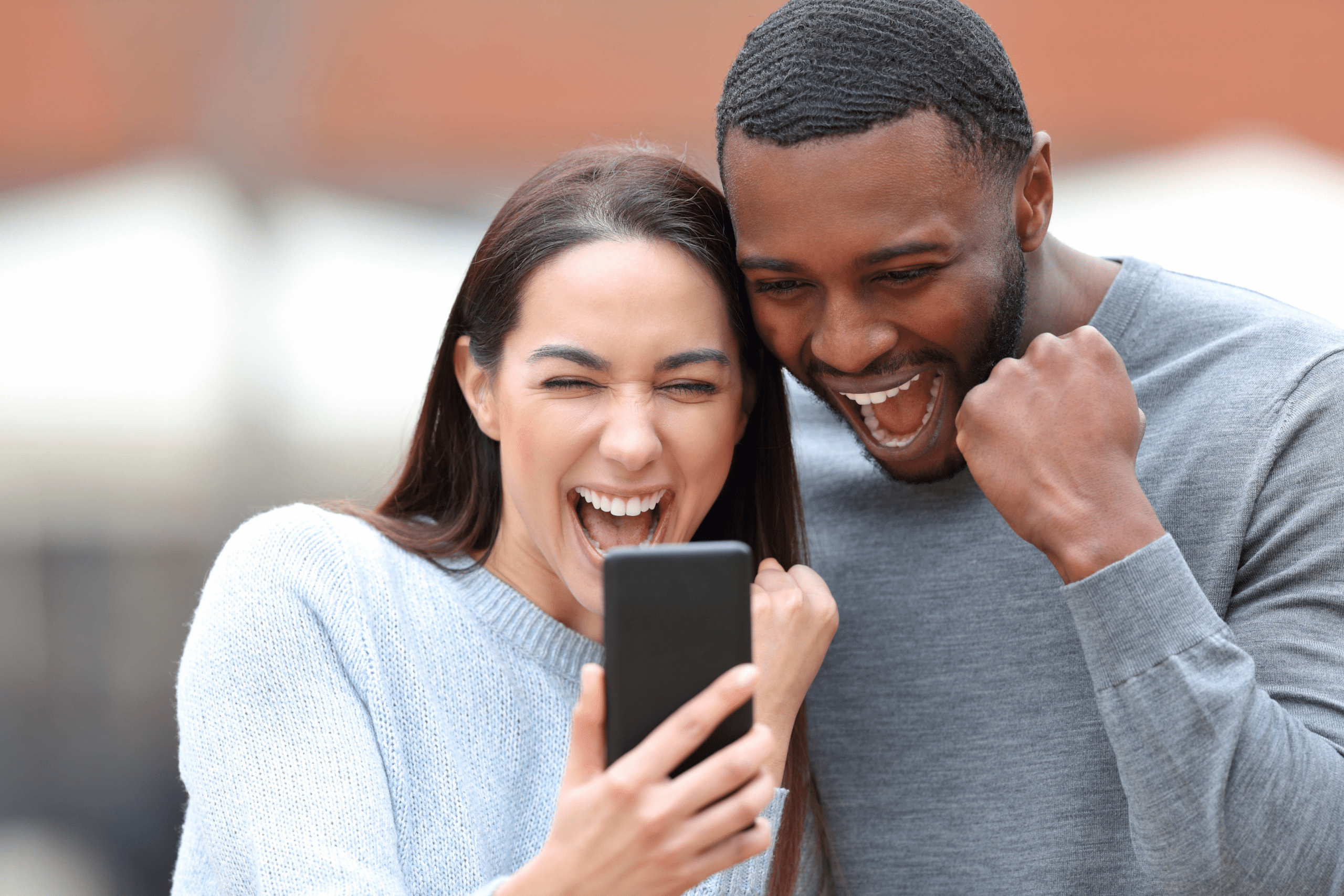 two people smiling and looking at a phone screen together