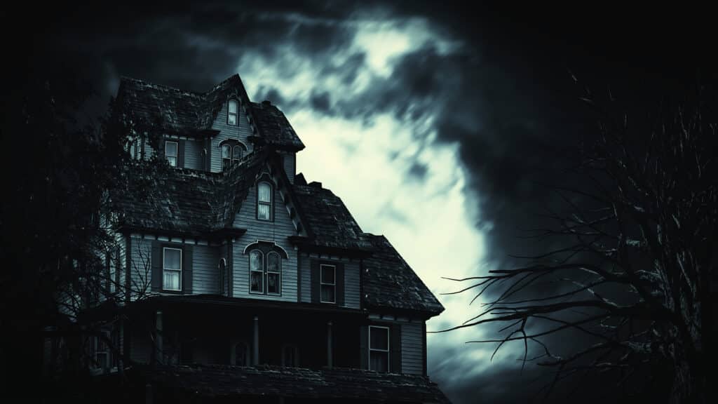 Abandoned house with a dark cloudy sky and barren trees.