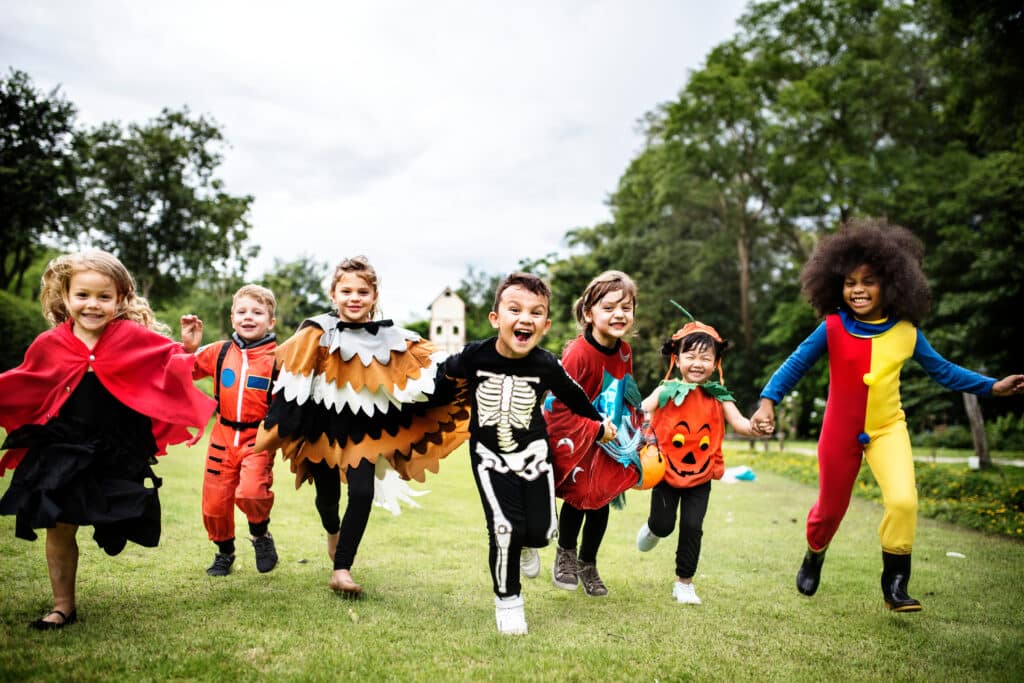 Little kids running down a trick or treat trail with Halloween costumes on 