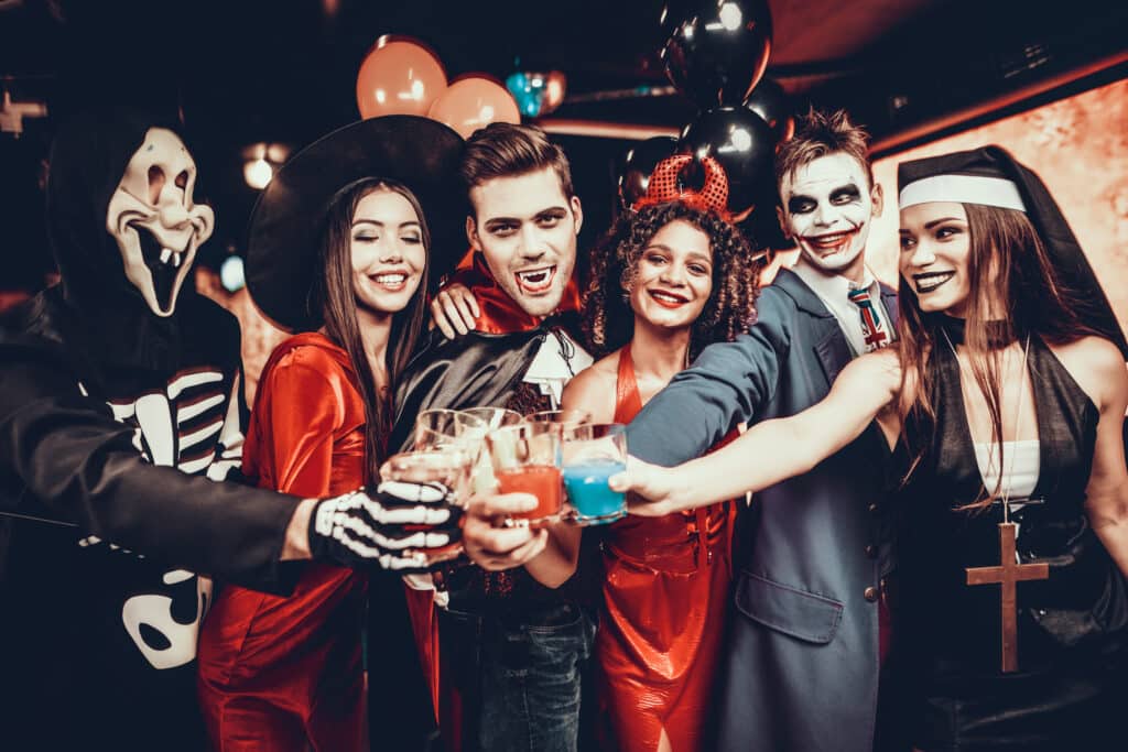 Friends in Halloween Costumes Drinking Cocktails.