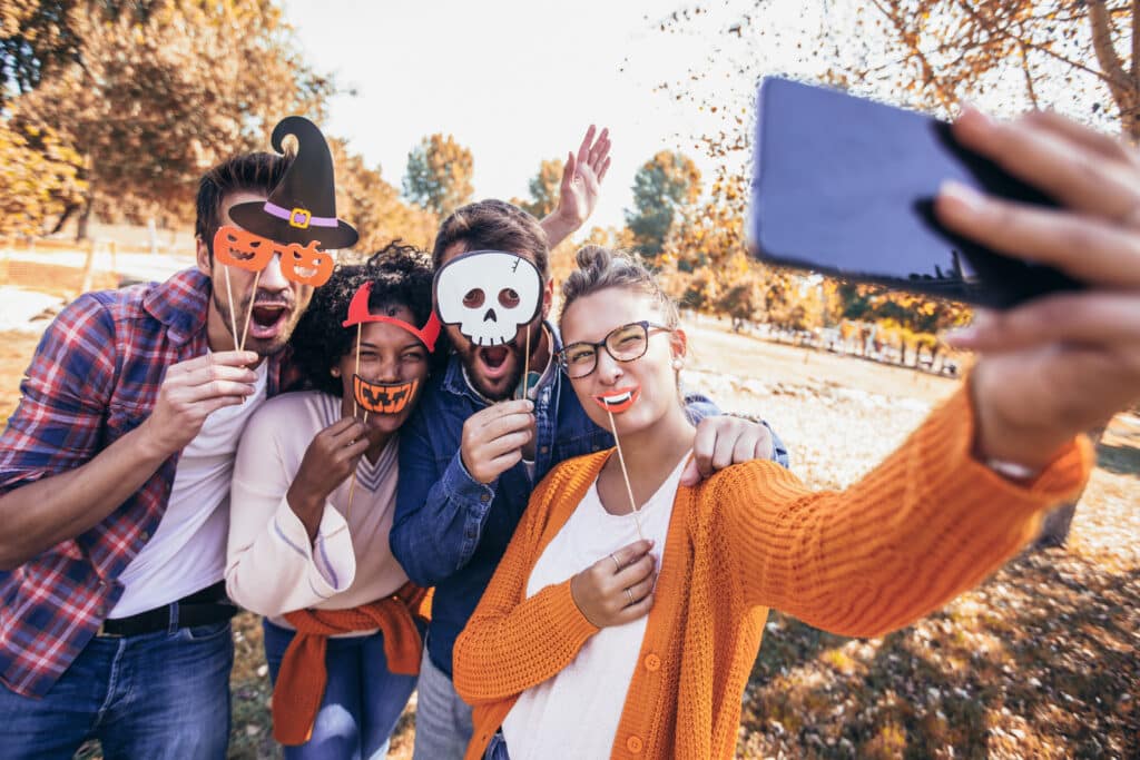 Group of young people hangout in the park.They are taking a selfie photo with halloween props.
