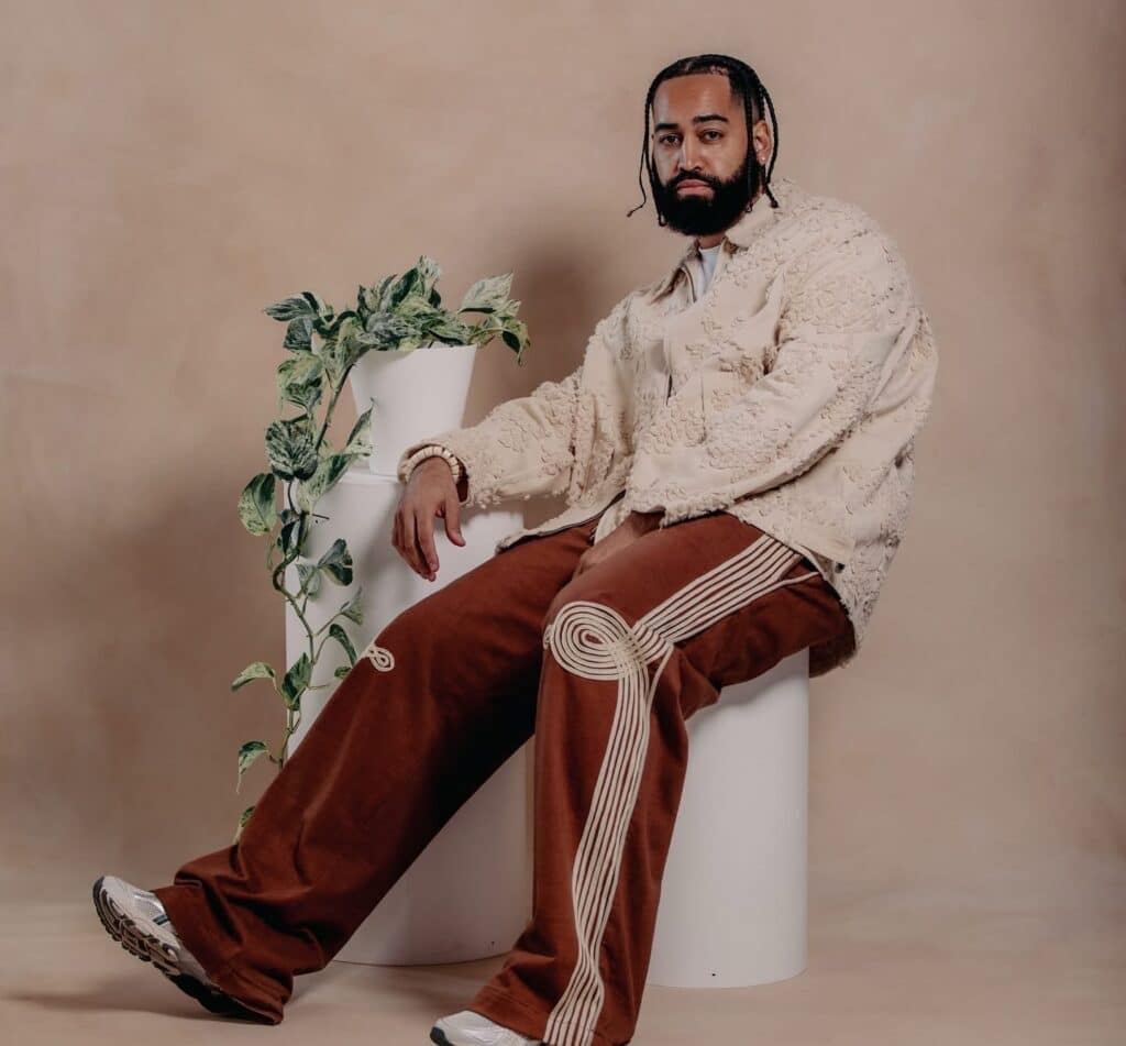 B Wise rap artist posing for headshot next to potted plant