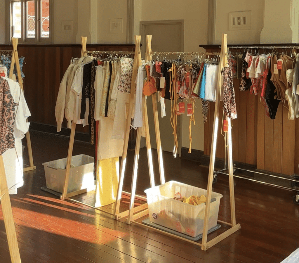 racks of clothes handing in an open wooden room with the morning light shining through the window